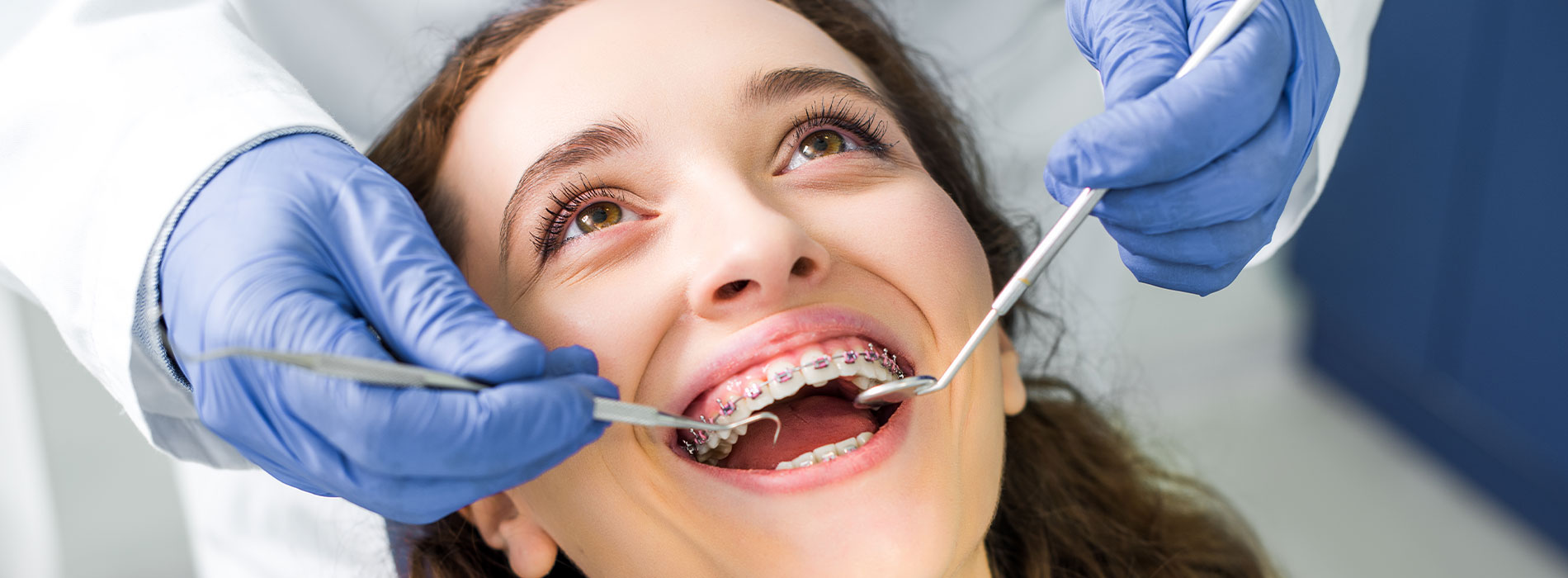 A woman receiving dental care with a smiling expression, assisted by a dental professional in a lab coat and gloves.