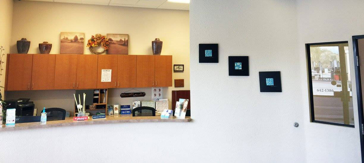 A well-lit reception area with a desk, computer monitor, and potted plant.