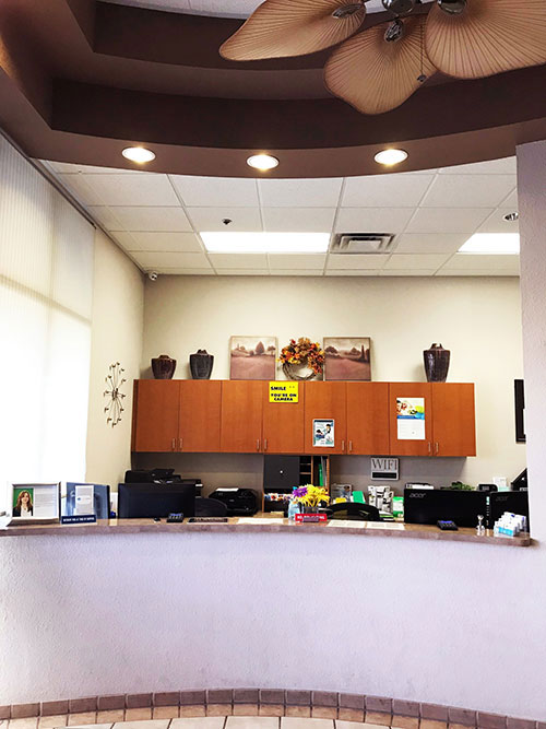 The image depicts an interior view of a reception area with a desk, cabinets, and a computer monitor.