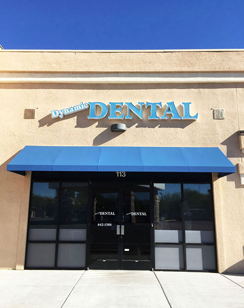 Dental office entrance with a blue awning and signage.