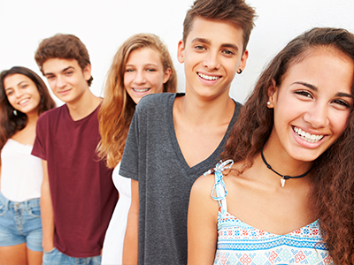 A group of young people posing for a portrait with smiles, standing against a white background.